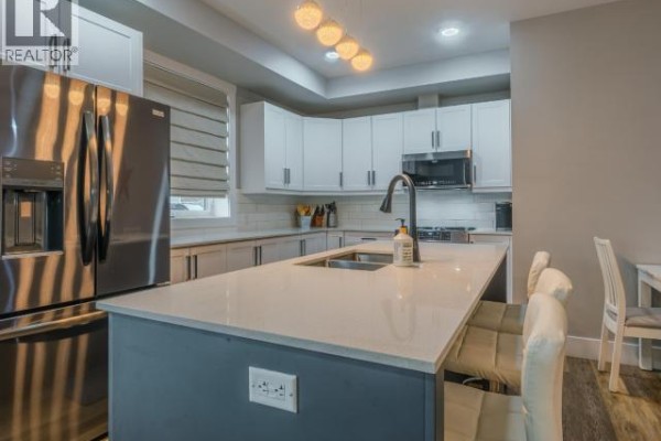 Balcony with two chairs, a small table, and a barbecue covered with a tarp. - 101-4841 School Draw Ave, Yellowknife