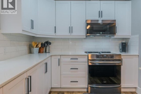 Bathroom with a vanity, a circular mirror, and a modern glass-enclosed shower. - 101-4841 School Draw Ave, Yellowknife