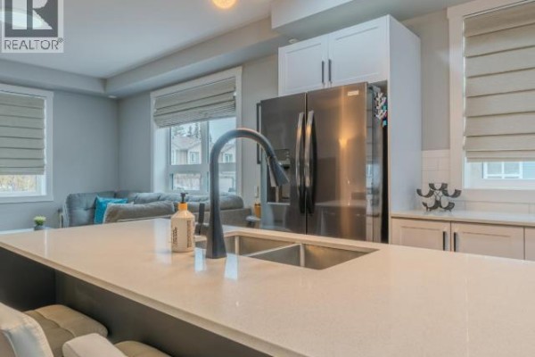 Bathroom with a vanity, a circular mirror, and a modern glass-enclosed shower. - 101-4841 School Draw Ave, Yellowknife
