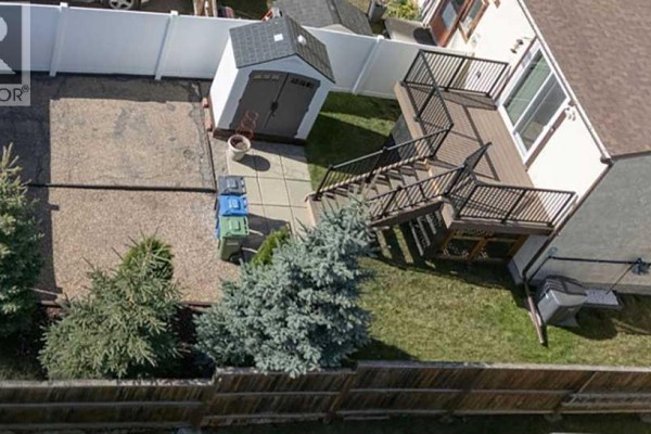 Aerial view of a backyard with a large wooden deck, shed, and fenced yard. - 101 Baile Close, Red Deer