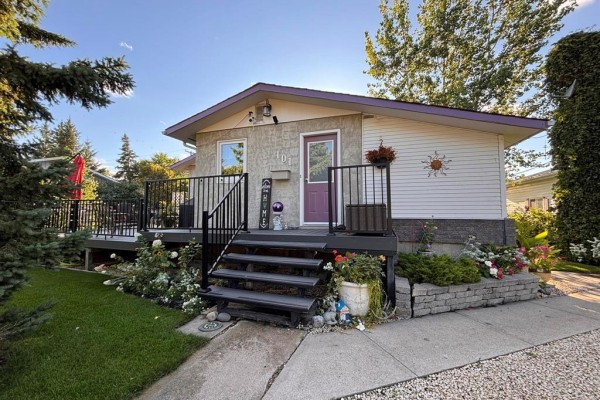Front view of the house with a purple door, deck, steps, and flower beds. - 101 Bay Street, Gladstone