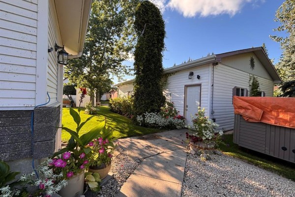 Side view of the house and garage with a walkway, plants, and a hot tub. - 101 Bay Street, Gladstone