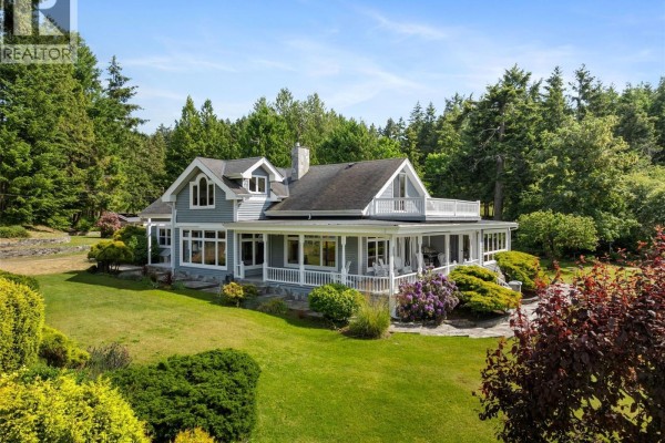 Large wooden barn-like building with arched windows, red umbrellas on an outdoor patio area. - 101 Church Bay Rd, Saturna Island