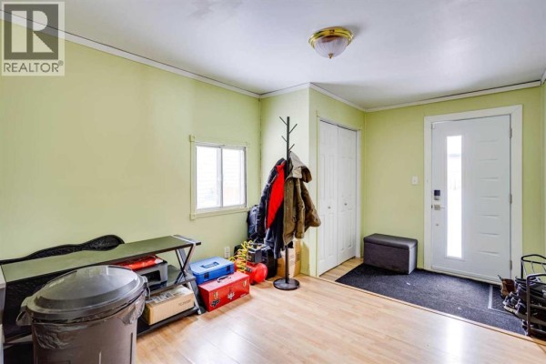 Living room with a large grey sectional sofa, ottoman, and light wood floors. - 101 Clausen Crescent, Fort Mcmurray