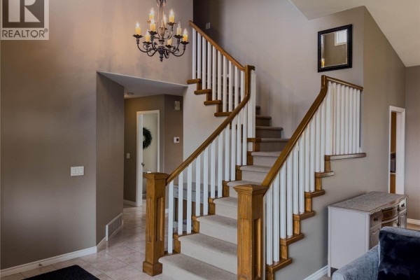 Interior staircase with a carpeted runner, white spindles, and oak banisters. - 101 Coppertree Court, Kamloops