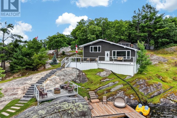 View of the waterfront home from the dock, showing a multi-level deck and stone steps. - 101 Healey Lake Water, The Archipelago