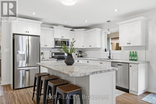 Kitchen with white shaker cabinets, granite countertops, stainless steel appliances, and an island. - 101 Tuffy Macdougall Court, Minto