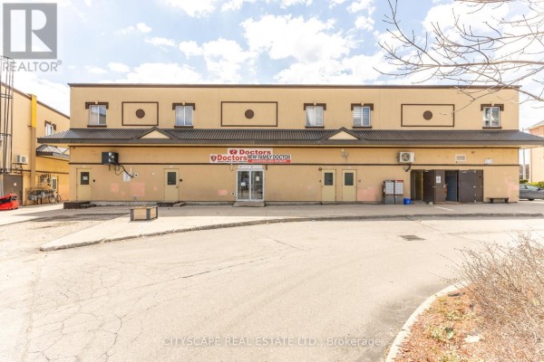 Rear view of the commercial building with loading bay doors and asphalt lot. - 101-bsmt - 2860 Denison Street, Markham