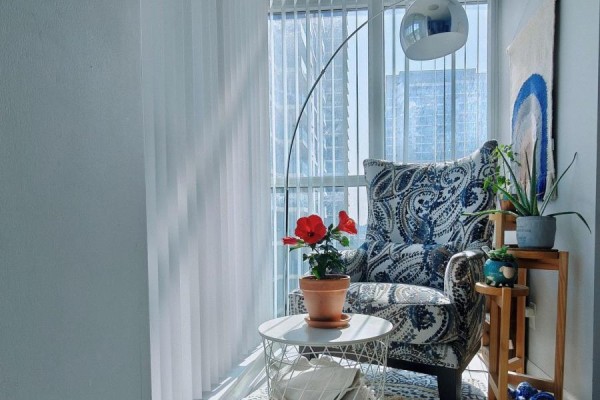 Armchair by a large window with vertical blinds and a white side table. - 1010 - 205 Sherway Gardens Road, Toronto