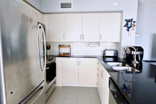 Compact kitchen with white cabinets, black countertops, and stainless steel appliances. - 1010 - 205 Sherway Gardens Road, Toronto