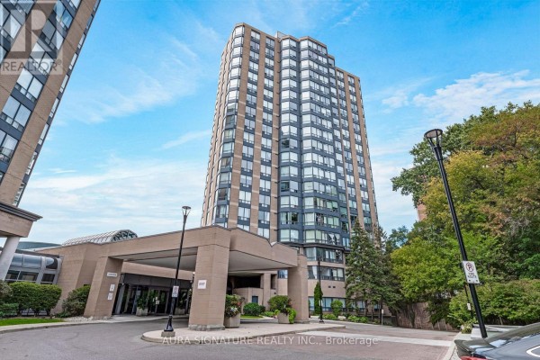 Exterior view of a tall apartment building with a covered entrance driveway. - 1010 - 3 Hickory Tree Road, Toronto