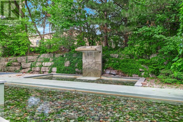 Water feature with a stone waterfall into a shallow pond with colorful pebbles. - 1010 - 3 Hickory Tree Road, Toronto