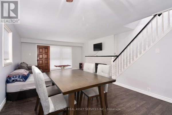 Dining area with a wooden table and chairs, next to a sofa and a white brick fireplace. - 1010 Kipps Lane, London East