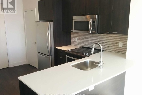 Kitchen with stainless steel refrigerator, dark wood cabinets, white quartz countertops, and a single sink. - 1011 - 30 Roehampton Avenue, Toronto