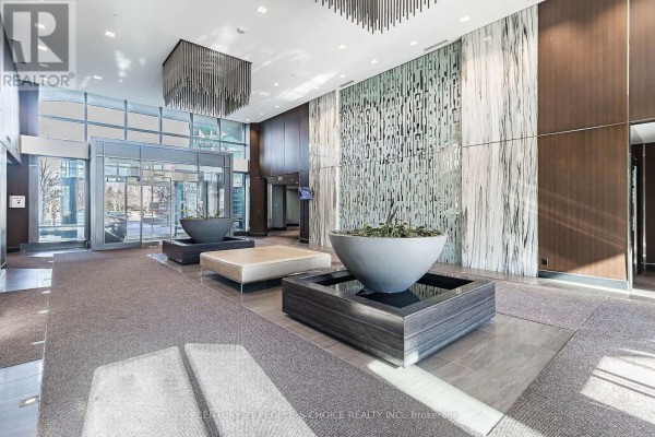 Modern building lobby with grey carpet, large planters, and wood accent walls. - 1012 - 205 Sherway Garden, Toronto