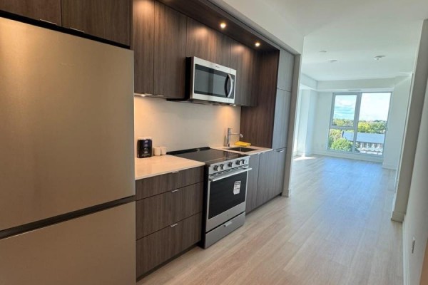 Kitchenette featuring dark wood cabinets, stainless steel appliances, and light wood floors. - 1012 - 25 Cordova Avenue, Toronto