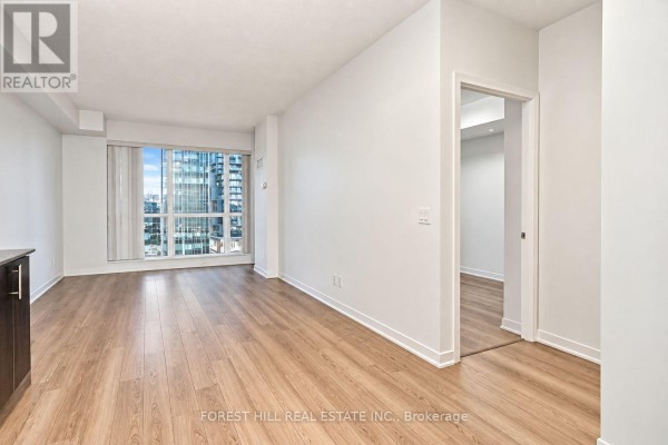 Empty living room with light wood floors, white walls, and city view. - 1012 - 60 Berwick Avenue, Toronto