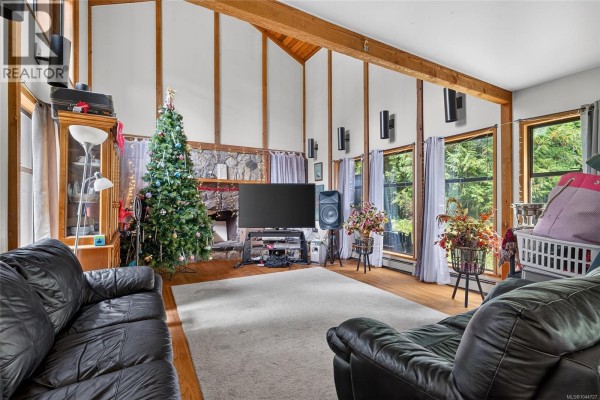 Living room with a fireplace, Christmas tree, large windows, and leather couches. - 1012 Fairdowne Rd, Errington
