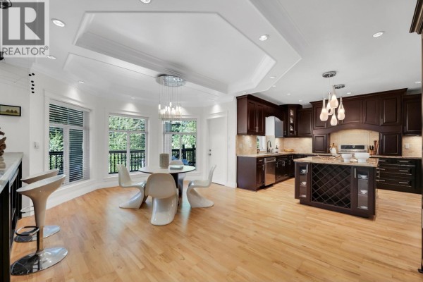 Kitchen island with granite countertop, dark wood cabinets, and modern pendant lights. - 1012 Jay Crescent, Squamish