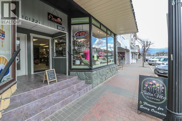 Entrance to a flower shop with a tiled staircase, glass doors, and a sidewalk with a flower display sign. - 10122/24 Main Street, Summerland