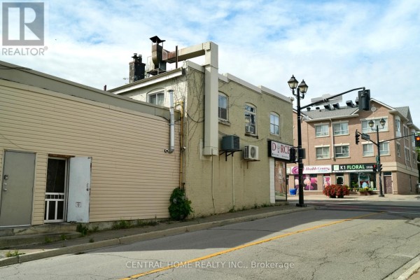 Side view of a beige commercial building with tan siding and other businesses in the background. - 10123 Yonge Street, Richmond Hill