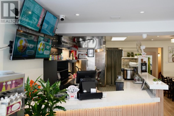 Restaurant counter with a cash register, menus on screens, and stainless steel kitchen equipment. - 10123 Yonge Street, Richmond Hill