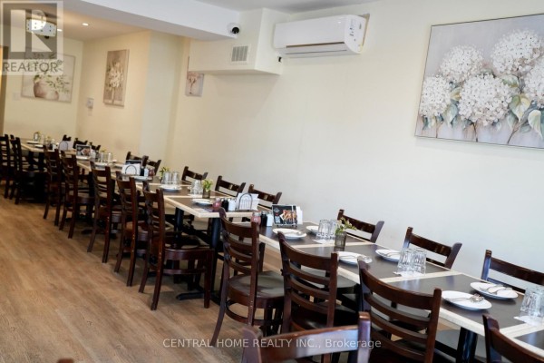 Dining area with rows of dark wood tables and chairs, set for customers. - 10123 Yonge Street, Richmond Hill