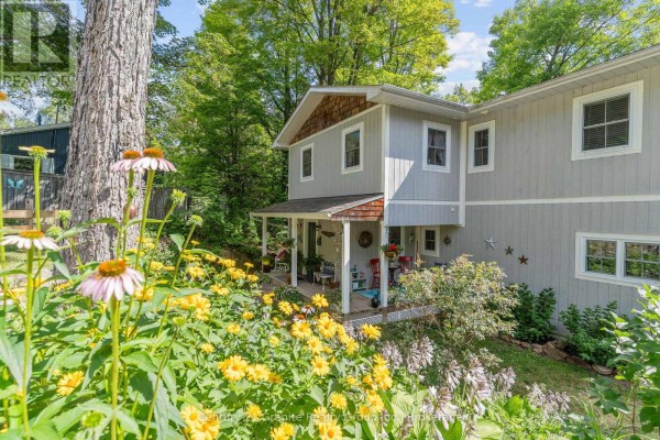 Close-up of front porch with colorful flowers and foliage in the foreground. - 1013 Neilburg Drive, Highlands East