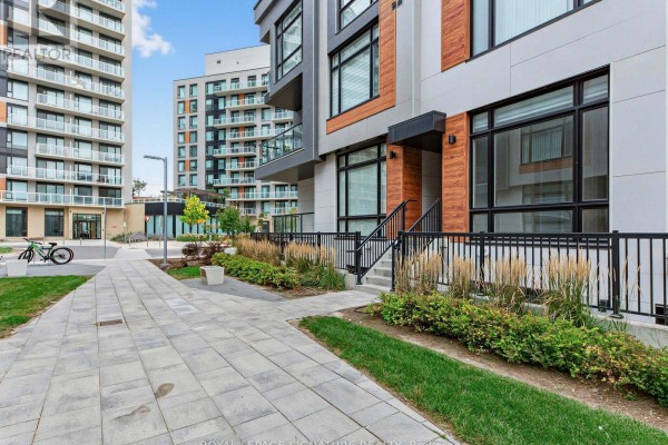 Paved walkway and green lawn leading to the entrance of a modern townhouse complex. - 1014 - 14 David Eyer Road, Richmond Hill
