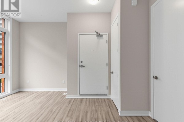 Interior hallway with a white entry door, light wood flooring, and two other white doors. - 1014 - 14 David Eyer Road, Richmond Hill