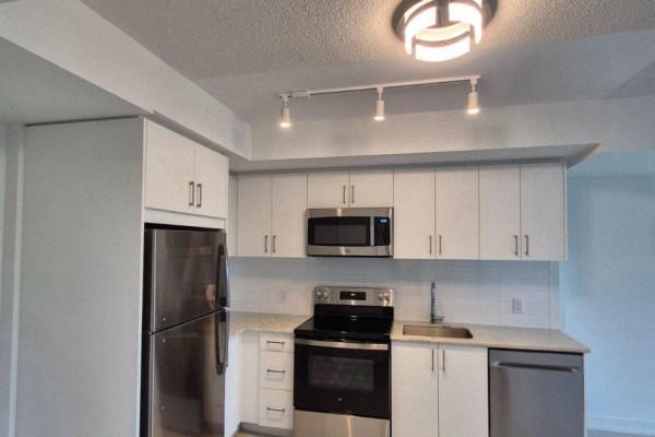 Kitchen with stainless steel refrigerator, microwave, stove, dishwasher, white cabinets, and granite countertops. - 1014 - 4010 Eglinton Avenue W, Toronto