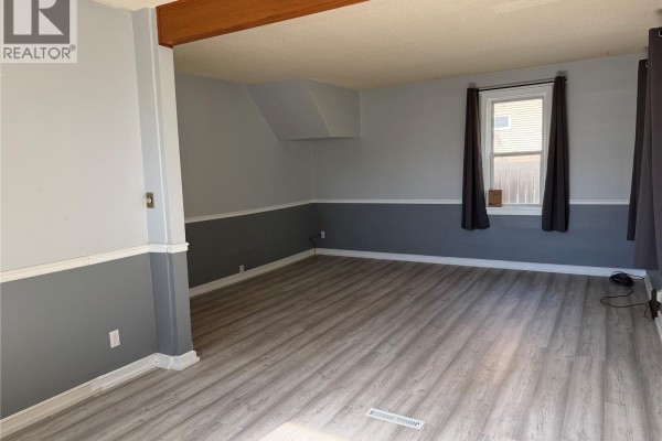 Interior view of a living room with grey and white two-toned walls and laminate flooring. - 1014 6th Avenue Nw, Moose Jaw