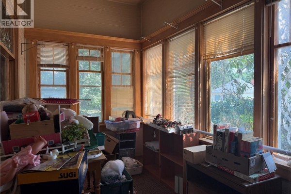 Sunroom with wood trim, large windows, and blinds, filled with storage. - 1014 Iroquois Street W, Moose Jaw