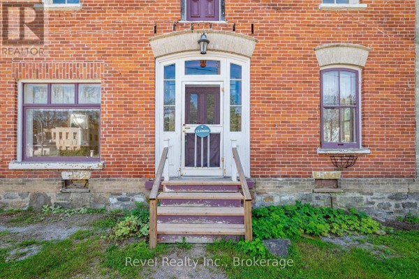 Close-up of the front entrance with a red brick facade and wooden steps. - 1014 Portage Road, Kawartha Lakes