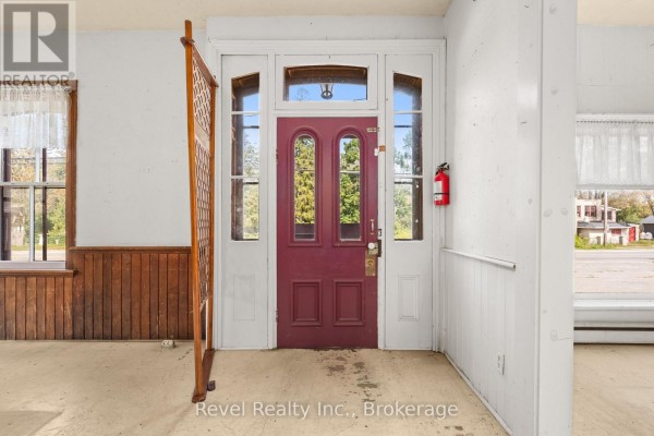 Interior view of a foyer with a red front door, glass panels, and wood trim. - 1014 Portage Road, Kawartha Lakes