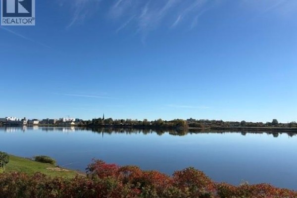 Expansive view of a wide blue river or lake with autumn foliage on the near bank. - 1015 Winton Crescent, Bathurst