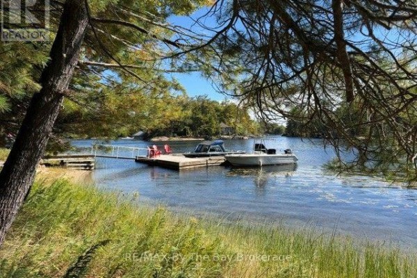 View from shore to a wooden dock with boats and red chairs on Georgian Bay. - 10158 Georgian Bay Shore, Georgian Bay