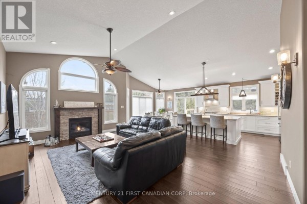 Open-concept living room with stone fireplace and modern kitchen island - 10159 Meadowlilly Crescent Lambton Shores
