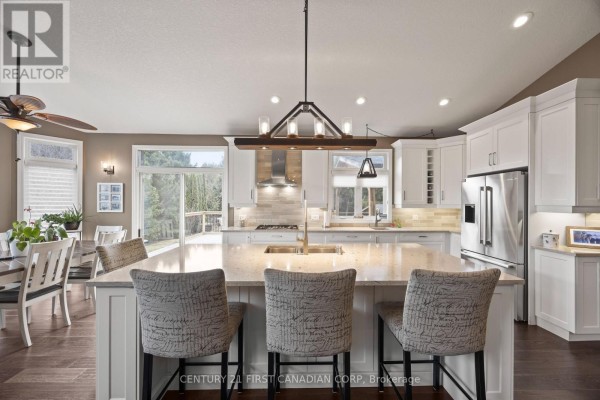 Modern kitchen with island, stainless steel appliances, and view to backyard - 10159 Meadowlilly Crescent Lambton Shores