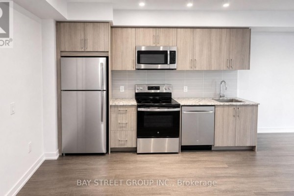 Modern kitchen with stainless steel appliances, light wood cabinets, and granite countertops. - 1016 - 4010 Eglinton Avenue W, Toronto