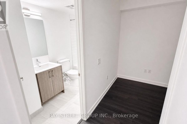 View from a hallway looking into a small room and a bathroom with a vanity and toilet. - 1016 - 4010 Eglinton Avenue W, Toronto