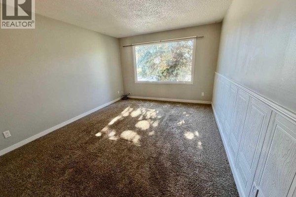 Empty bedroom with beige carpet and wainscoting. - 1016 20 Avenue, Coaldale