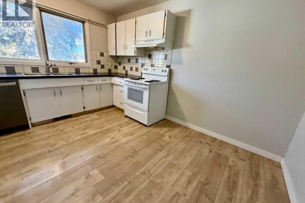 Kitchen with white cabinets, checkered backsplash, and white appliances. - 1016 20 Avenue, Coaldale