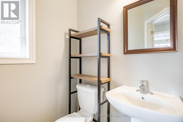 Pedestal sink, toilet, and shelving unit in a bathroom - 1016 Wright Drive Midland