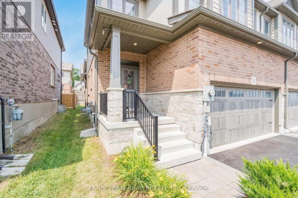 Close-up of a townhouse entrance with a covered porch, concrete steps, and black metal railings. - 1016 Wright Drive, Midland