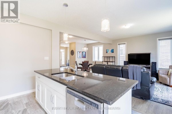 Kitchen island with sink and dishwasher overlooking living room with sofa and TV - 1016 Wright Drive Midland