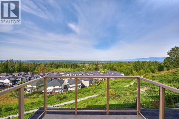 Backyard with a hot tub, green lawn, and wooden fence overlooking houses. - 10163 247 Street, Maple Ridge