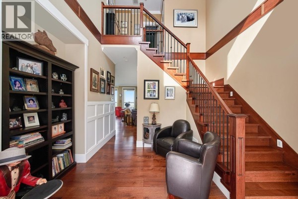 Living room with a fireplace, sofa, chairs, dining area, and large windows. - 10163 247 Street, Maple Ridge