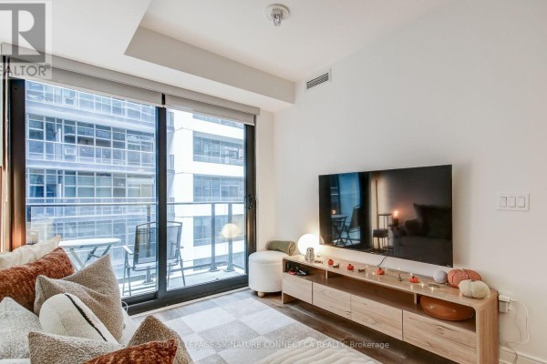Living room with a sofa, media console with television, and floor-to-ceiling windows showing a city view. - 1017 - 1 Jarvis Street, Hamilton