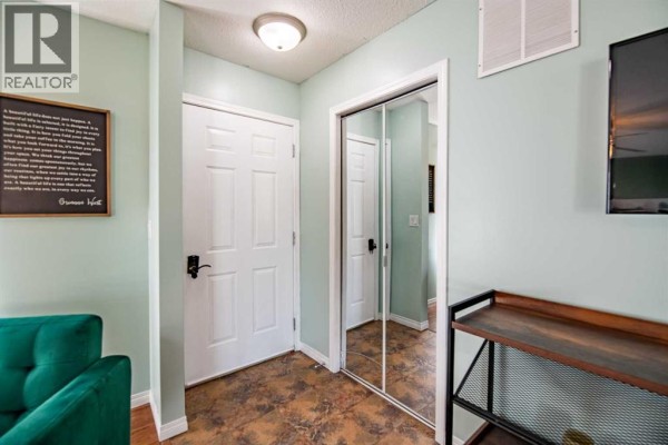 Interior hallway with light green walls, white doors, mirrored closet, and a console table. - 1018, 25054 South Pine Lake Road, Rural Red Deer County